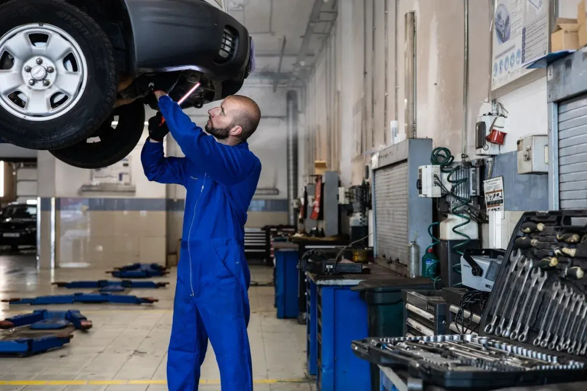 Illustrative stock photograph: Technician inspecting a raised vehicle